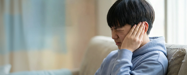 귀를 감싸 쥐고 있는 청소년