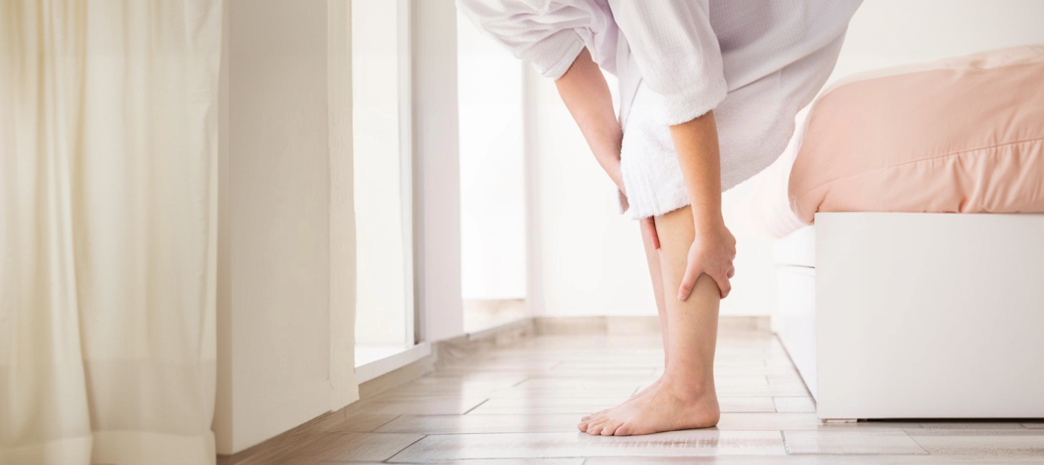 침대에서 다리를 잡고 있는 하지불안증후군 환자